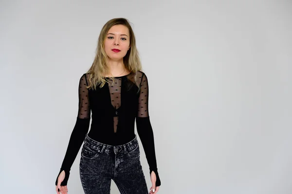 Concepto de una mujer hablando con la cámara. Una foto de una chica muy sonriente con el pelo rizado largo y hermoso en una camiseta negra sobre un fondo blanco está de pie justo en frente de la cámara . — Foto de Stock