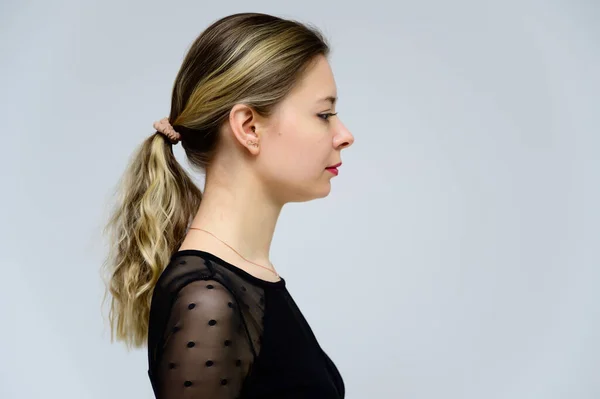 Conceito de uma mulher de perfil em frente à câmara. Foto de perfil de uma menina muito sorridente com cabelo encaracolado em uma camiseta preta em um fundo branco . — Fotografia de Stock