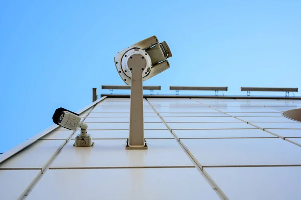 Foto de um belo céu azul em um dia claro ensolarado contra o fundo de câmeras de CCTV em um edifício — Fotografia de Stock