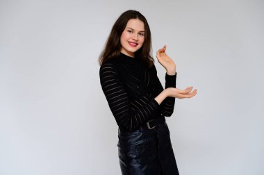 Beyaz arka planda yetişkin bir kız. Siyah etekli ve siyah kazaklı güzel bir esmer kızın fotoğrafı gülümsüyor ve kameranın önünde farklı pozlarda farklı duygular gösteriyor..