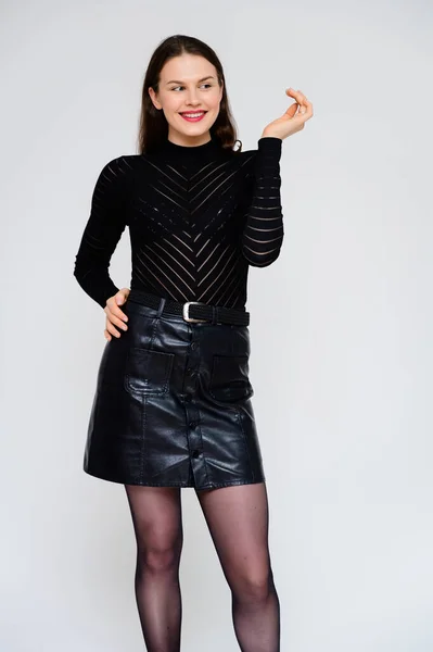Concept volwassen meisje op een witte achtergrond. Verticale foto van een mooie full-length brunette meisje in een zwarte rok en zwarte trui glimlachen en tonen verschillende emoties in verschillende poses. — Stockfoto