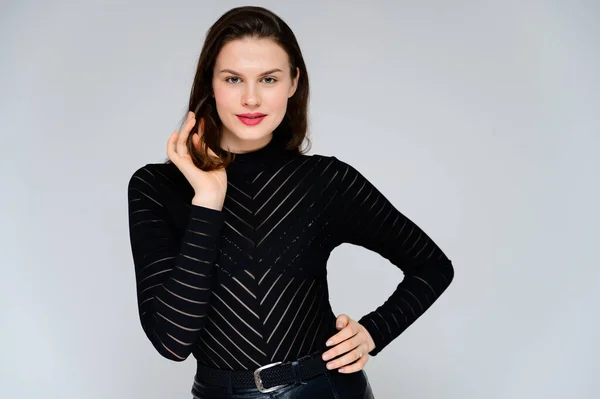 Conceito menina adulta em um fundo branco. Grande foto de uma menina morena bonita em uma camisola preta sorrindo e mostrando emoções diferentes em diferentes poses bem na frente da câmera . — Fotografia de Stock