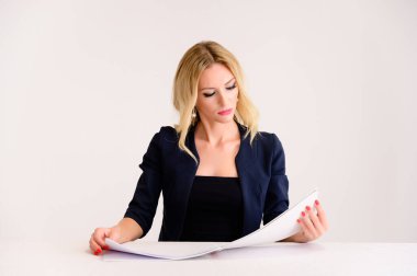 İş konsepti. Güzel bir kadın muhasebeci portresi - mükemmel makyajlı, beyaz arka planda güzel saçı olan, elinde klasörle bir masada oturan.