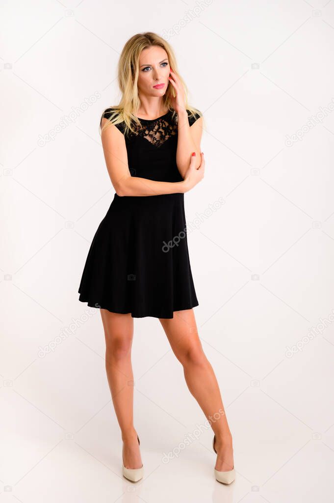 Full length portrait of a pretty slim blonde model in a black dress on a white background. Stylish, fashionable, youth, sexy. It is in different poses.