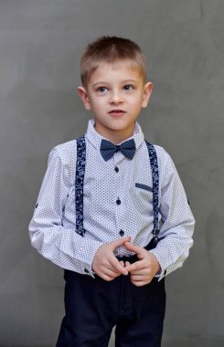 Gri sanat arka planında 10 yaşında şirin bir okul çocuğunun portresi. Dik durur, duygularını gösterir, tatlı mutluluğu.