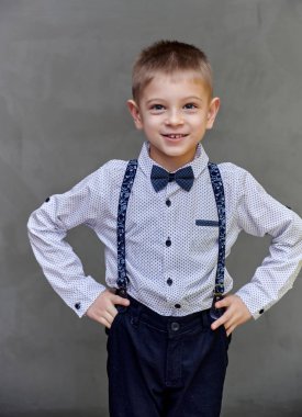 Gri sanat arka planında 10 yaşında şirin bir okul çocuğunun portresi. Dik durur, duygularını gösterir, tatlı mutluluğu.