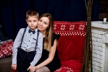 Mutlu bir ailenin portresi: anne ve 10 yaşında tatlı bir çocuk evde, kanepede, çatı katı tarzında. Kameranın önünde oturmak, duygularını göstermek, gülümsemek.