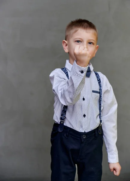 Portré egy aranyos 10 éves iskolás fiúról szürke művészeti háttérrel. Egyenesen állni, öklökkel fenyegetve, érzelmeket mutatni, édes boldogságot. — Stock Fotó