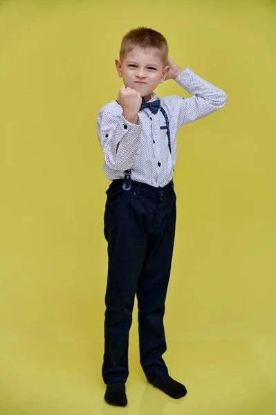 Portré egy aranyos 10 éves iskolás fiúról sárga háttérrel. Teljes magasságban áll, érzelmeket mutat, beszél.. — Stock Fotó