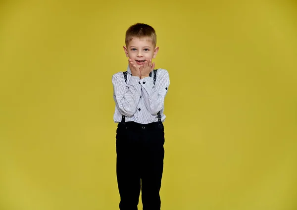 바지와 셔츠를 입은 노란 배경의 10 세 남학생의 귀여운 사진. 카메라 앞에 서서 감정을 보여 주고. — 스톡 사진