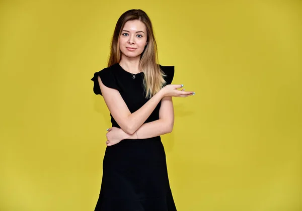 Porträt einer hübschen jungen lächelnden Frau auf gelbem Hintergrund in einem schwarzen Kleid mit langen glatten Haaren. direkt vor der Kamera stehen, Emotionen zeigen, in verschiedenen Posen reden. — Stockfoto