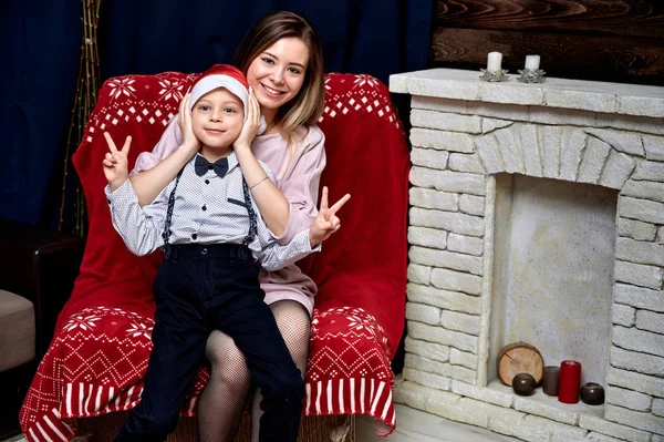 Portrait of a beautiful girl with long hair in a pink dress sitting at home on a sofa in a loft style. Sitting right in front of the camera, showing happy emotions, smile — Stock Photo, Image