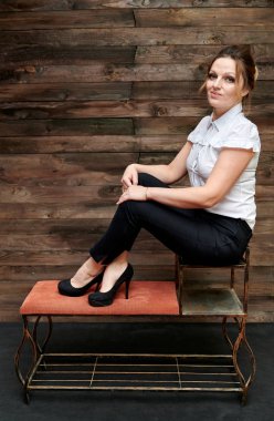 40 yaşında, ahşap bir arka planda güzel makyajlı güzel bir kadının portresi. Kameranın önünde bir tezgahta oturuyor ve gülümsüyor. İş konsepti.