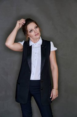 Gri arka planda iş elbisesi giymiş 40 yaşında güzel bir kadının portresi. İş konsepti. Ciddi bir ruh haliyle kameranın önünde dikiliyorsun..