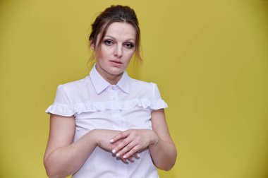 İş konsepti. 40 yaşında, güzel, yetişkin bir kadının portresi. Sarı arka planda iş elbisesi içinde güzel bir makyajı var. Gülümseyerek kameranın önünde duruyorsun..