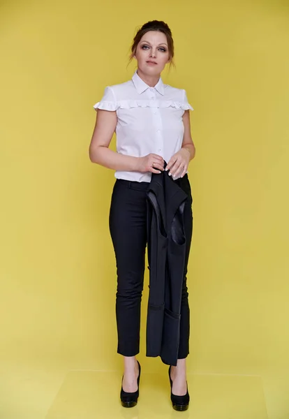 Business concept. Full-length portrait of an adult pretty woman of 40 years old with good makeup in a business suit on a yellow background. Standing right in front of the camera with a smile. — Stock Photo, Image