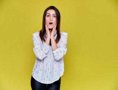 Bir ofis çalışanı, öğretmen, yönetici konsepti. Beyaz iş gömleği giymiş güzel esmer bir kızın portresi. Gülümsüyor, sarı arka planda kameraya konuşuyor..