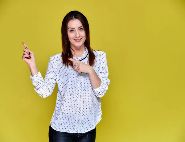 El concepto de un oficinista, profesor, gerente. Retrato de una guapa morena en blusa blanca de negocios sonriendo, hablando con la cámara sobre un fondo amarillo . — Foto de Stock