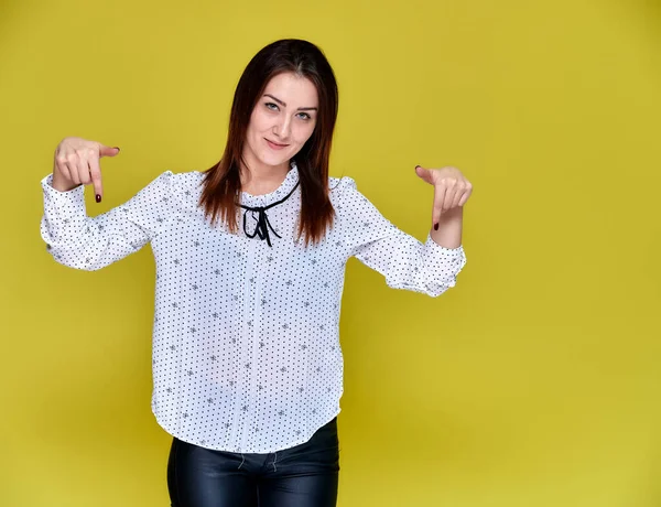 El concepto de un oficinista, profesor, gerente. Retrato de una guapa morena en blusa blanca de negocios sonriendo, hablando con la cámara sobre un fondo amarillo . — Foto de Stock