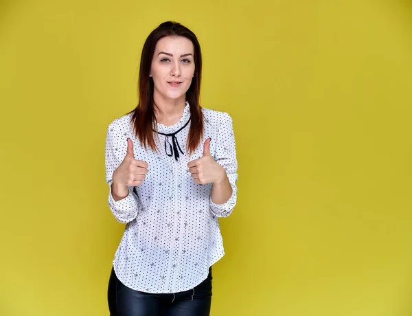 El concepto de un oficinista, profesor, gerente. Retrato de una guapa morena en blusa blanca de negocios sonriendo, hablando con la cámara sobre un fondo amarillo . — Foto de Stock