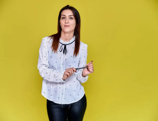 El concepto de un oficinista, profesor, gerente. Retrato de una guapa morena en blusa blanca de negocios sonriendo, hablando con la cámara sobre un fondo amarillo . — Foto de Stock