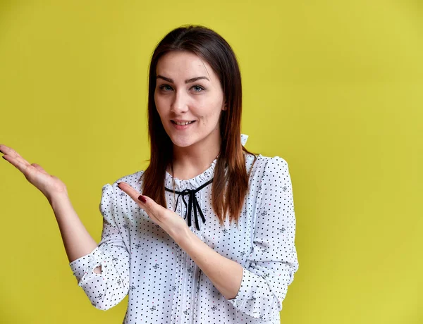 El concepto de un oficinista, profesor, gerente. Retrato de una guapa morena en blusa blanca de negocios sonriendo, hablando con la cámara sobre un fondo amarillo . — Foto de Stock