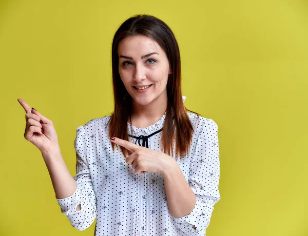 O conceito de um funcionário de escritório, professor, gerente. Retrato de uma menina morena bonita em uma blusa branca de negócios sorrindo, conversando com a câmera em um fundo amarelo . — Fotografia de Stock