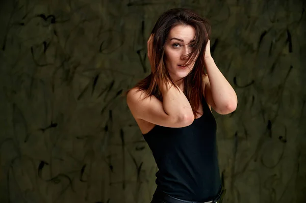 Krásný koncept, stylový portrét. Fotografie krásné okouzlující brunetky dívka v černém tričku s letícími vlasy na šedé módní originální pozadí. — Stock fotografie