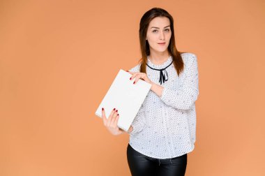 Elinde klasör olan sekreter konsepti. Beyaz bluzlu, düz siyah saçlı güzel bir kadının portresi. Kameranın önünde duruyor, gülümsüyor, turuncu bir arka planda duygularını gösteriyor..