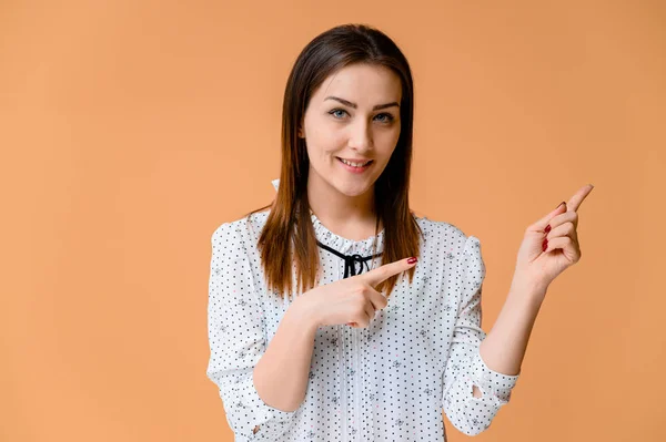 Concepto de secretario. Retrato de una mujer bonita, gerente en una blusa blanca con el pelo suave y oscuro. Él está de pie justo delante de la cámara, sonriendo, mostrando emociones sobre un fondo naranja . — Foto de Stock