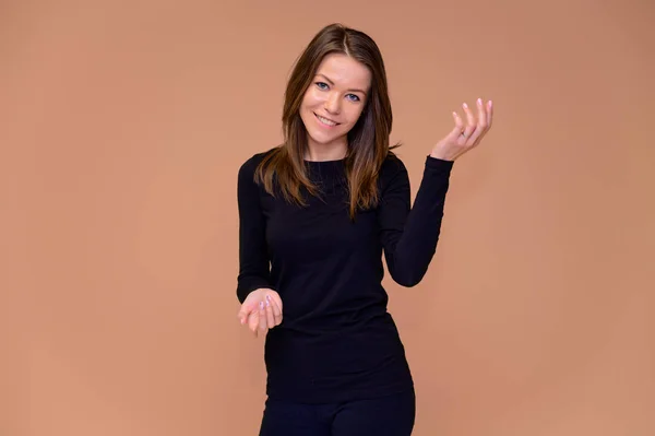 Retrato de una linda chica en una camiseta negra con hermosos dientes. Se para frente a la cámara, sonríe, muestra emociones sobre un fondo rosado. Concepto de una joven con una sonrisa de dientes blancos . — Foto de Stock