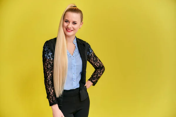 Portrait of a manager woman in a business suit with long beautiful hair and excellent make-up on a yellow background. Concept business blonde girl stands in front of the camera. — Stock Photo, Image
