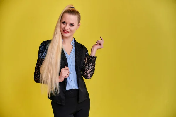 Retrato de uma mulher gerente em um terno de negócios com cabelo longo e bonito e excelente maquiagem em um fundo amarelo. Conceito de negócios menina loira fica na frente da câmera . — Fotografia de Stock