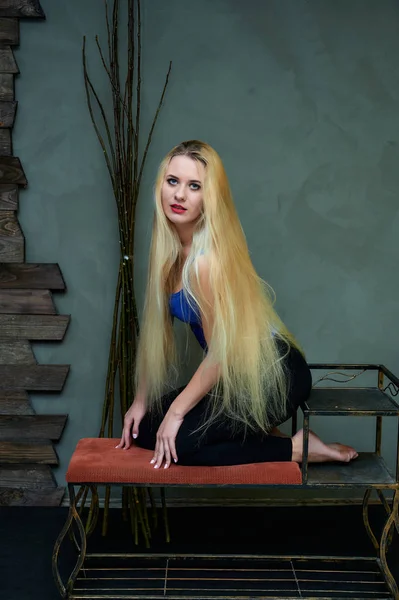 Concepto artístico de un retrato modelo con estilo. Retrato de una mujer delgada con pelo largo y hermoso y excelente maquillaje sobre un fondo gris creativo de madera en el estilo loft . — Foto de Stock