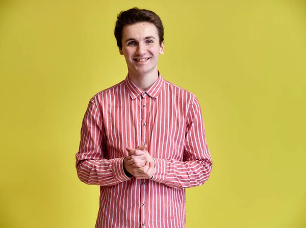 Portrett av en kjekk ung mann med kort frisyre og et bredt smil i en rosa skjorte på gul bakgrunn. Søt ser på kameraet, står rett . – stockfoto