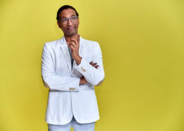 Kısa saçlı, beyaz dişli, sarı arka planda beyaz ceketli genç bir Afrikalı Amerikalı 'nın portresi. Kameranın önünde dikilip konuşmak..