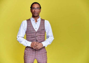 Kısa saçlı, beyaz dişli, sarı arka planda iş elbisesi giymiş genç bir Afro-Amerikan 'ın portresi. Kameranın önünde dikilip konuşmak..