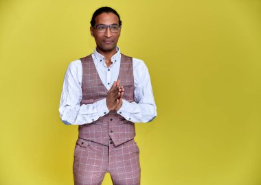 Kısa saçlı, beyaz dişli, sarı arka planda iş elbisesi giymiş genç bir Afro-Amerikan 'ın portresi. Kameranın önünde dikilip konuşmak..