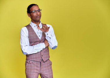 Kısa saçlı, beyaz dişli, sarı arka planda iş elbisesi giymiş genç bir Afro-Amerikan 'ın portresi. Kameranın önünde dikilip konuşmak..