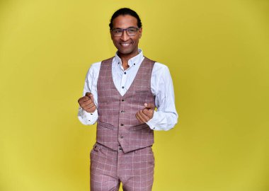 Kısa saçlı, beyaz dişli, sarı arka planda iş elbisesi giymiş genç bir Afro-Amerikan 'ın portresi. Kameranın önünde dikilip konuşmak..