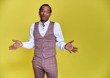 Kısa saçlı, beyaz dişli, sarı arka planda iş elbisesi giymiş genç bir Afro-Amerikan 'ın portresi. Kameranın önünde dikilip konuşmak..