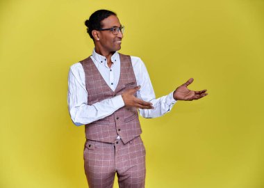 Kısa saçlı, beyaz dişli, sarı arka planda iş elbisesi giymiş genç bir Afro-Amerikan 'ın portresi. Kameranın önünde dikilip konuşmak..