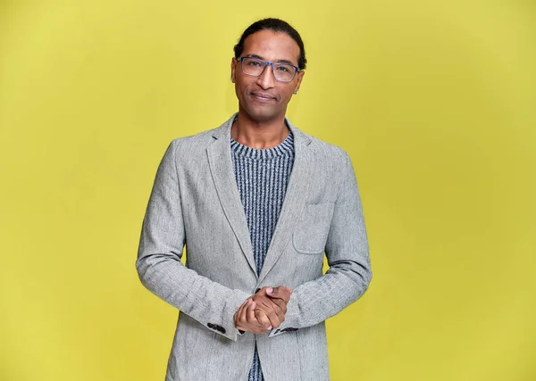 Retrato de un joven afroamericano con el pelo corto y una sonrisa de dientes blancos con una chaqueta gris sobre un fondo amarillo. De pie y hablando delante de la cámara . —  Fotos de Stock