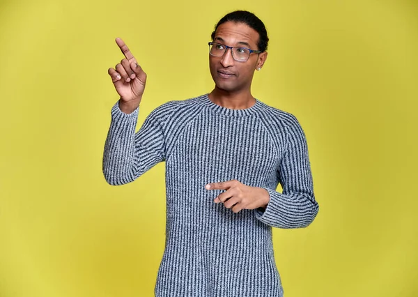 Porträtt av en ung afroamerikansk man i glasögon med en kort frisyr och med ett vitt-tandat leende i en grå tröja på en gul bakgrund. Stå och prata framför kameran. — Stockfoto
