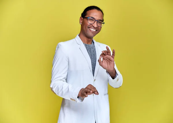 Porträtt av en ung afroamerikansk man med korta frisyrer och ett vitt-tandat leende i en vit jacka på gul bakgrund. Stå och prata framför kameran. — Stockfoto