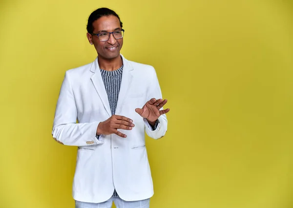 Retrato de un joven afroamericano con cortes de pelo cortos y una sonrisa de dientes blancos con una chaqueta blanca sobre un fondo amarillo. De pie y hablando delante de la cámara . —  Fotos de Stock