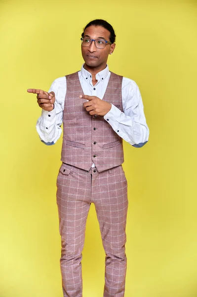 Retrato vertical Joven con afroamericano de pelo corto en un traje de negocios sobre un fondo amarillo. De pie y hablando delante de la cámara . —  Fotos de Stock