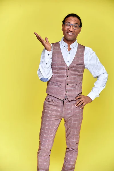 Retrato vertical Joven con afroamericano de pelo corto en un traje de negocios sobre un fondo amarillo. De pie y hablando delante de la cámara . —  Fotos de Stock