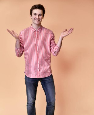 Pembe arka planda pembe gömlekli, kısa saçlı, beyaz dişli gülümseyen beyaz bir beyaz adamın dikey portresi. Kameranın önünde el ele tutuşup konuşuyorlar..