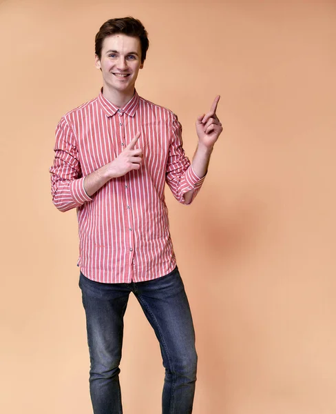 一个白种人的年轻男子的垂直肖像，短发，白牙微笑，粉红背景的粉红衬衫。 站在镜头前，手牵着手说话. — 图库照片